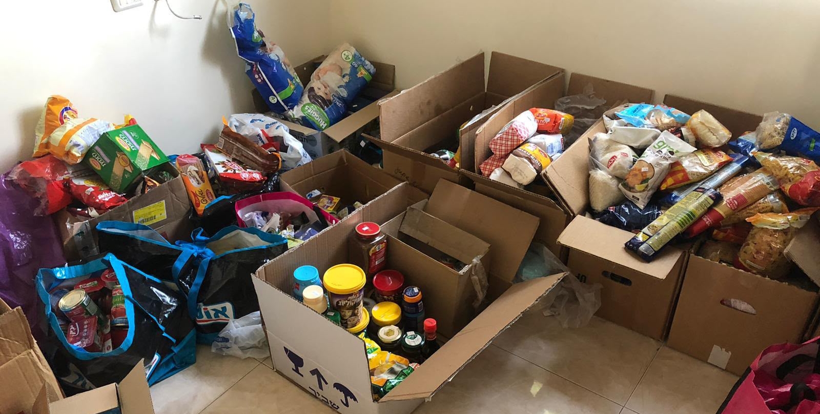 קרטונים ושקיות מלאים במוצרי מזון עבור המשפחות.